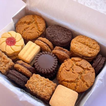 A pink-lined box of assorted biscuits including jam flowers.