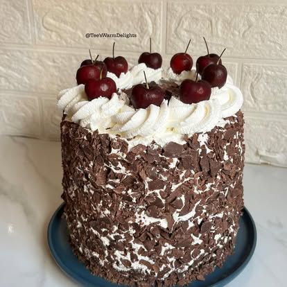 A black forest cake covered in chocolate shavings and topped with cherries.