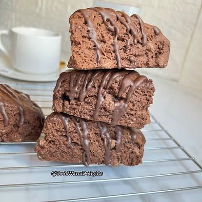 A stack of three chocolate cookies drizzled with melted chocolate on a cooling rack.