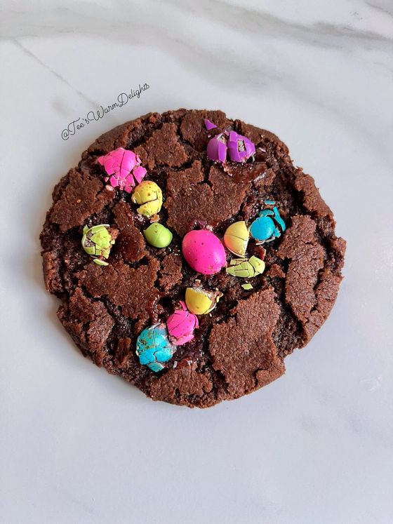 A chocolate cookie topped with pastel speckled eggs.