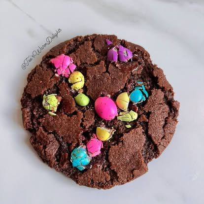 A chocolate cookie decorated with bright speckled mini eggs.