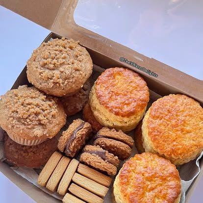 A box holding crumble muffins, scones and small biscuits together.