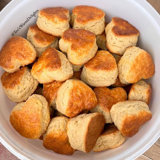A white bowl piled with freshly baked plain and blueberry scones.