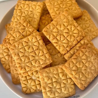 A plate piled with square stamped shortbread biscuits.