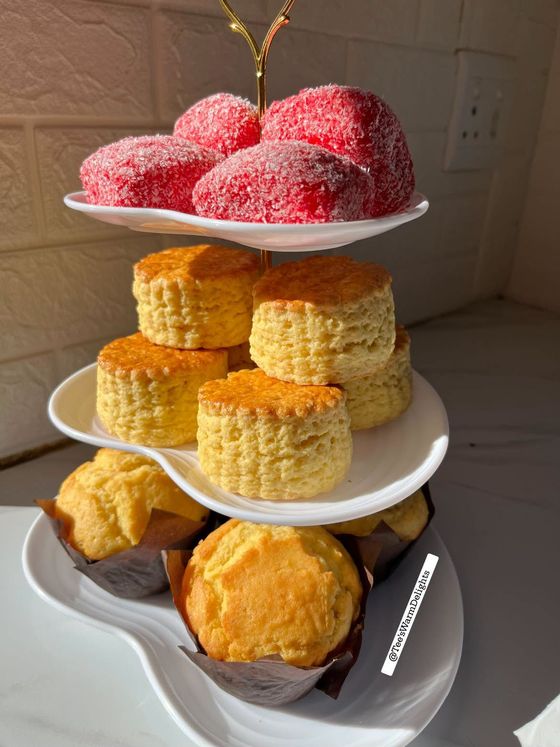 A tiered stand with strawberry whirls, scones and muffins.